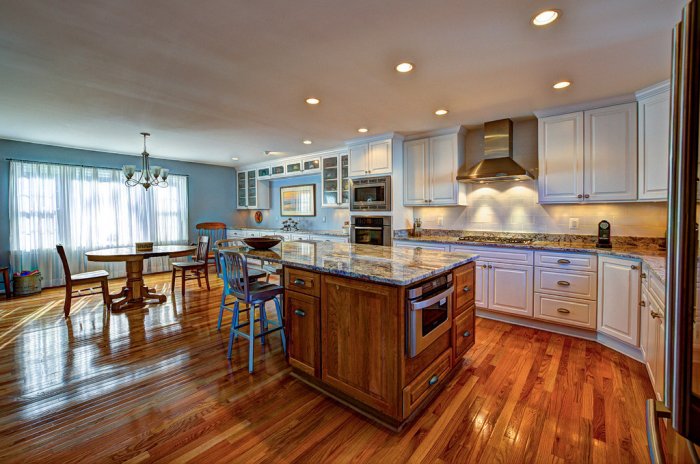 large kitchen with island, kitchen table with wood flooring